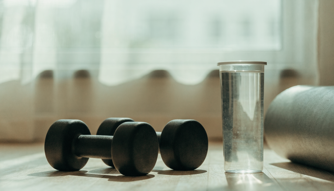 Bright minimalist home gym with dumbbells and a water bottle in soft daylight