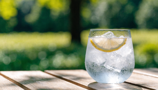 Frosted glass of iced water with lemon on a sunny outdoor table