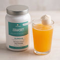 Collagen Complex + tub beside a glass of orange drink and a scoop