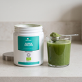 Super Greens tub beside a glass of green drink and a scoop