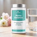 Women's menopause supplement on a table with a glass of water
